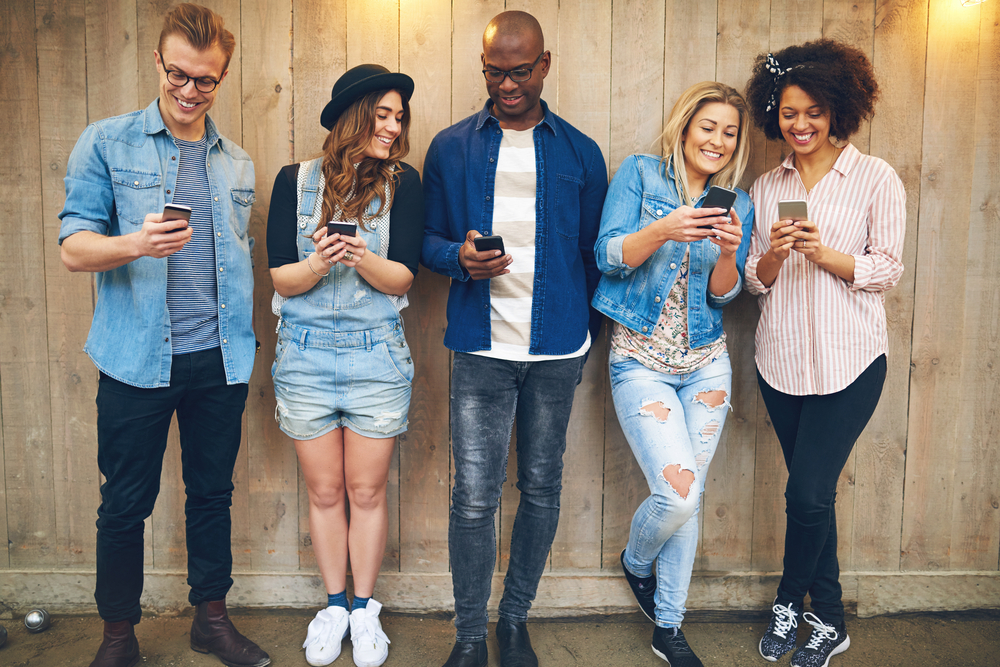 Group of 5 friends hanging out on their phones