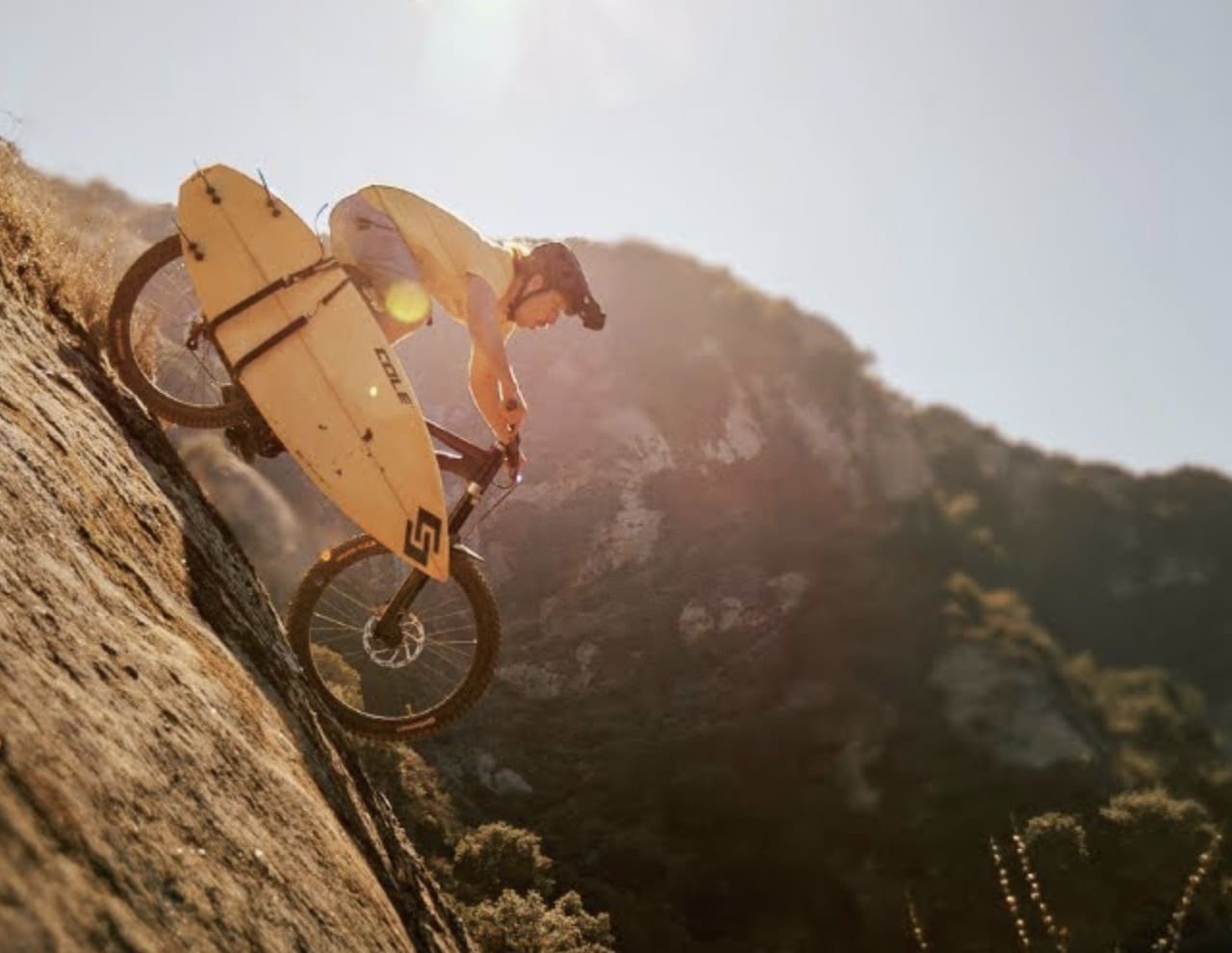 Laguna Beach mountain biking with surfboard attached.