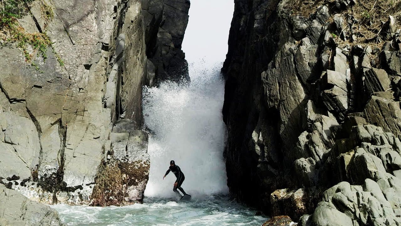 Surfers ride "God's Crack" rock formation in Northern Japan.
