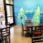 A room with tables and shares and a beautiful mural