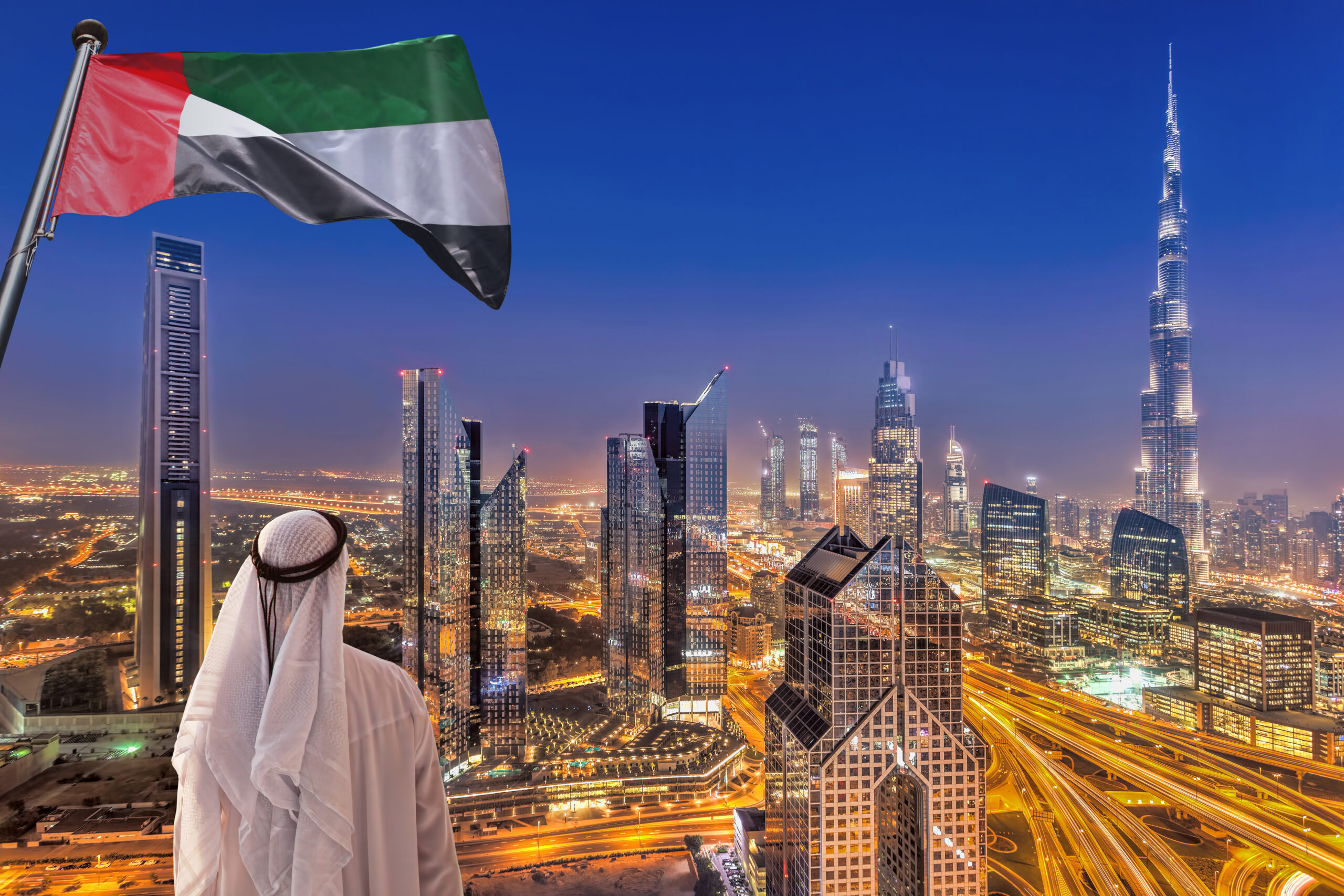 Arabian man watching night cityscape of Dubai with modern futuristic architecture in United Arab Emirates