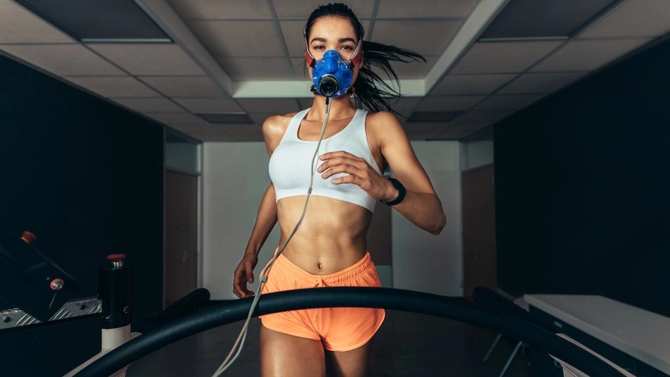 Athlete running on a treadmill wearing a metabolic testing mask