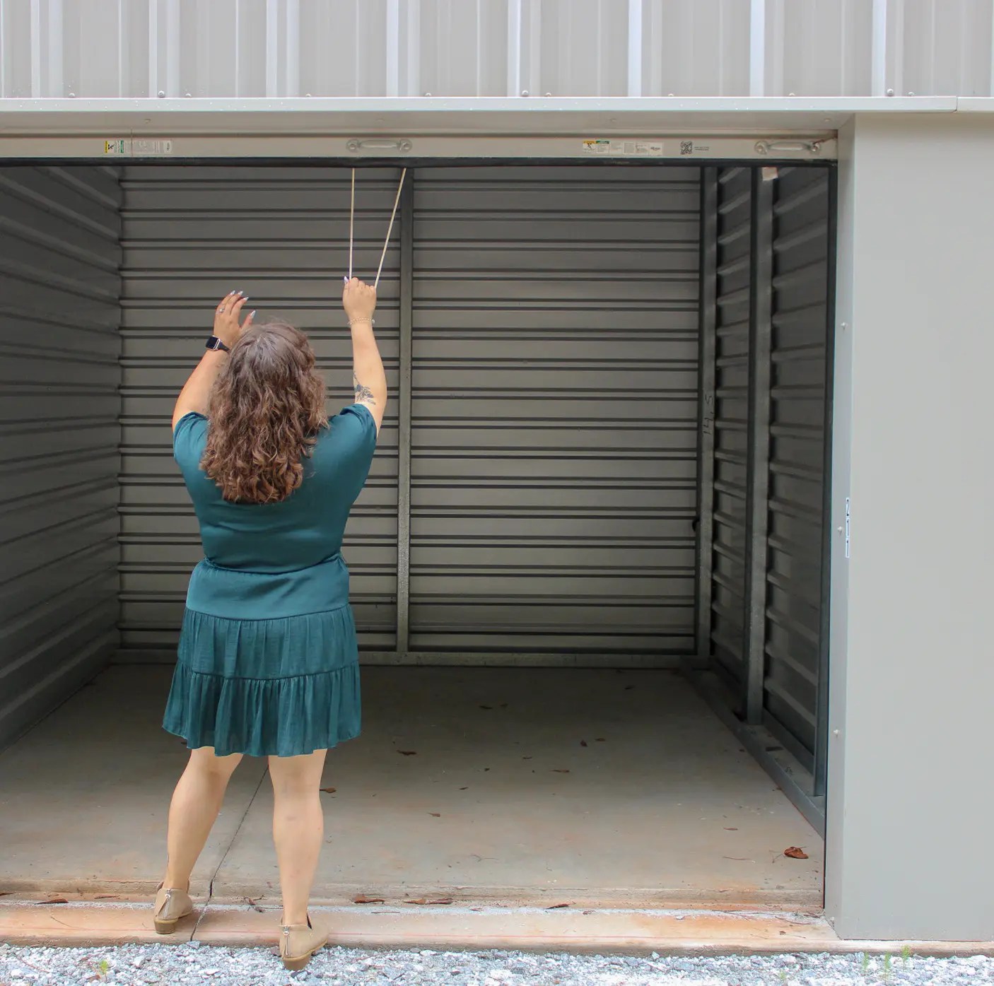 Young brunette woman pulling down door to clean, durable storage unit.