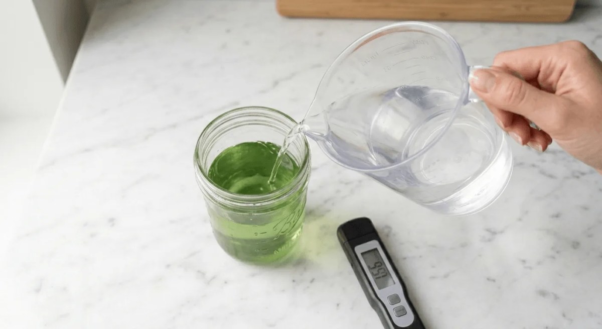 Pouring plain water into a mason jar reservoir beside a digital EC meter