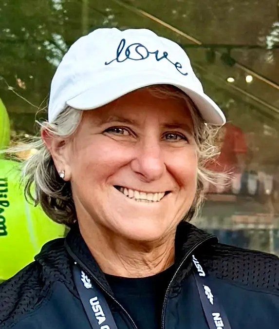 Dr. Ellen Markowitz smiling at the camera with a white baseball cap on with text reading "love" in blue font.