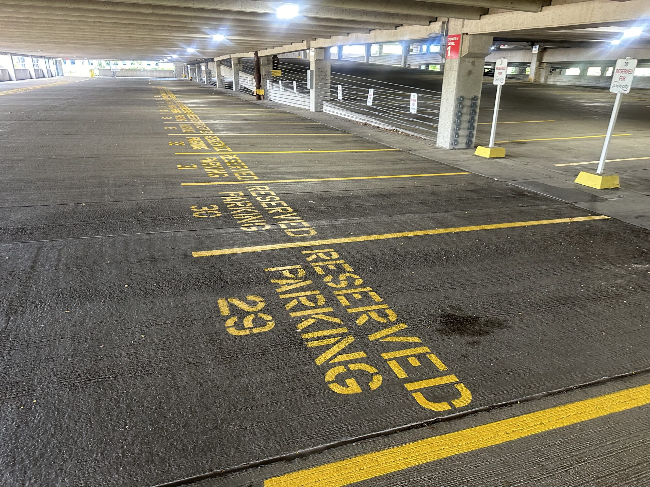 Empty parking garage with reserved spots marked in yellow paint. Spot numbers 31, 32, and 33 are visible in a well-lit area.
