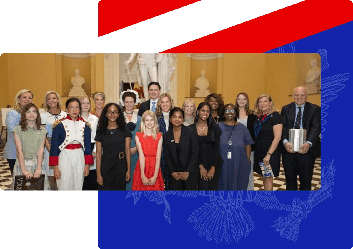 A diverse group of people posing indoors with a statue and busts in the background on a checkered floor.
