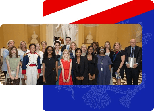 A diverse group of people posing indoors with a statue and busts in the background on a checkered floor.