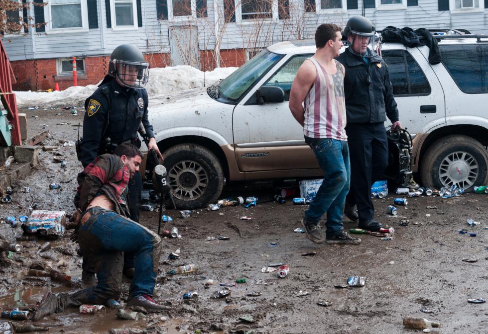 JASON PICARD An officer helps a highly intoxicated man to his feet while another escourts an apparently sober individual away from the scene that was forcibly dispersed of several hundred people less than a half hour before, behind an Amherst residence near the corner of North Pleasant St. and Fearing St., on Saturday afternoon, March 8th. - Jason Picard |