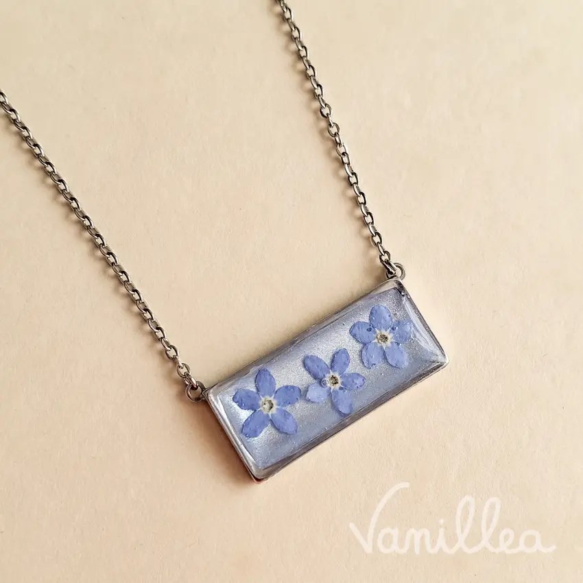 Collier rectangle floral argenté porté avec fleurs de myosotis