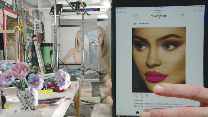 A video still captures a finger swiping through Instragram, an artist's cluttered studio in the background.