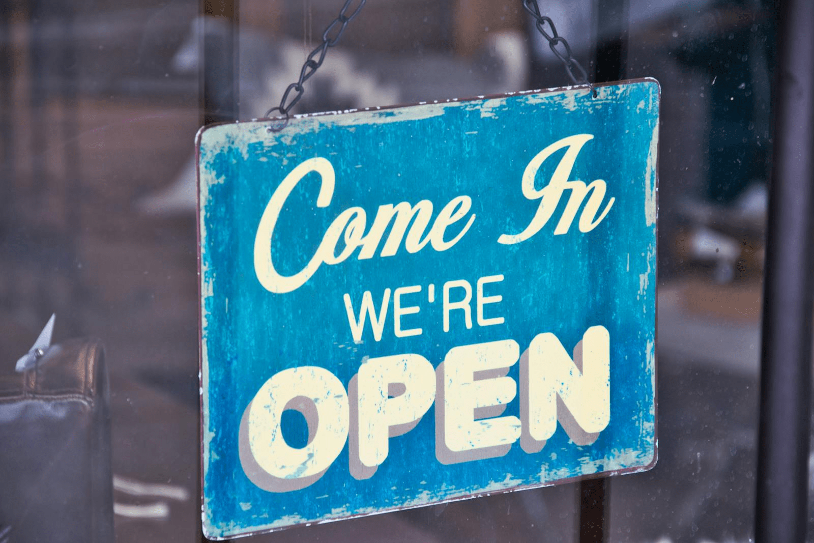 Retro blue open sign on a shop glass door inviting customers in.