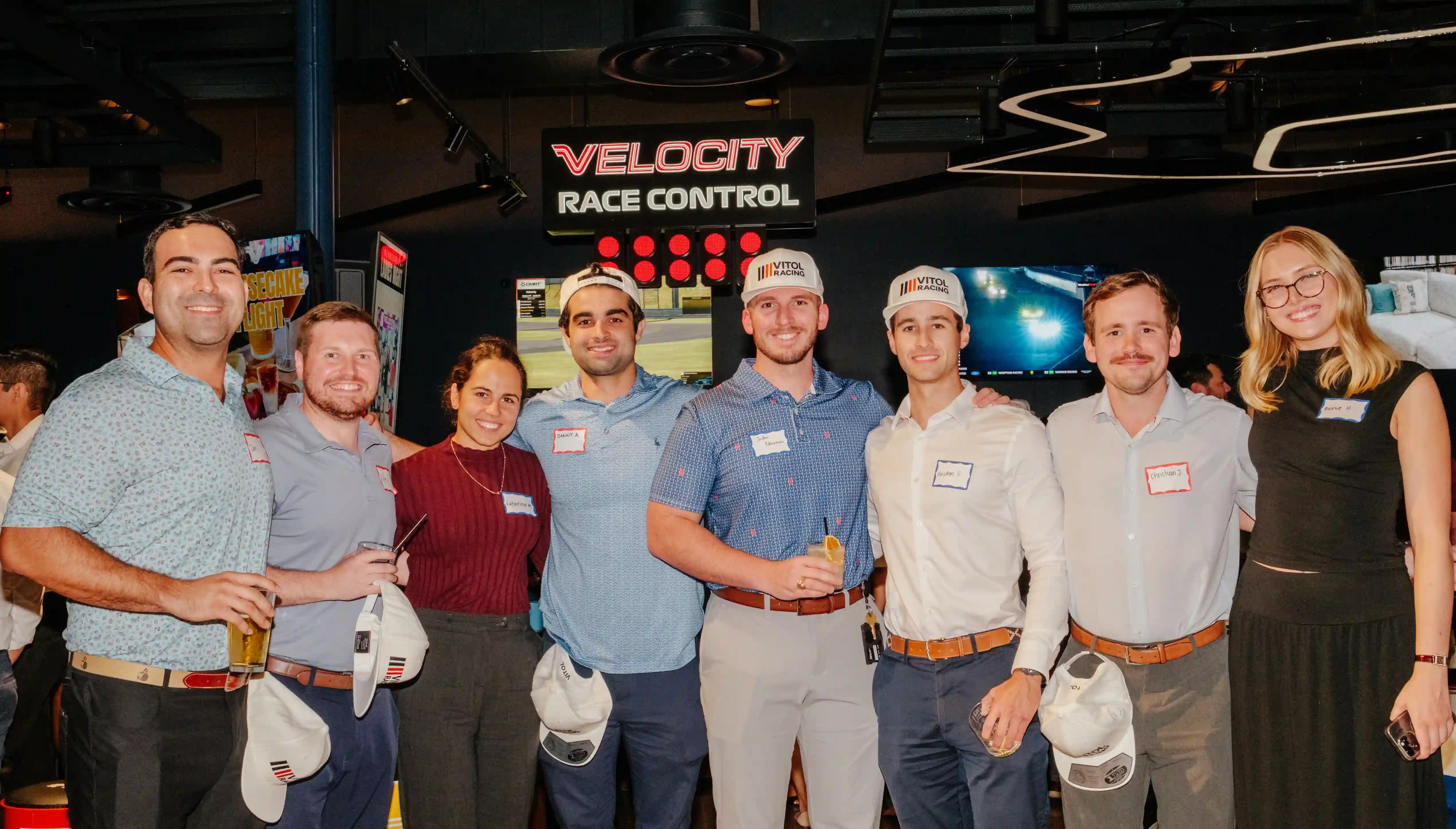 Group of coworkers pose for team photo at the Velocity Sim Racing Lounge group event space in Houston.