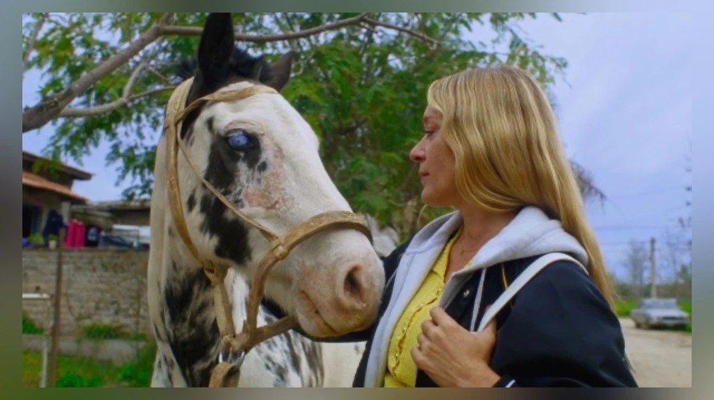 Chloë Sevigny standing next to a horse