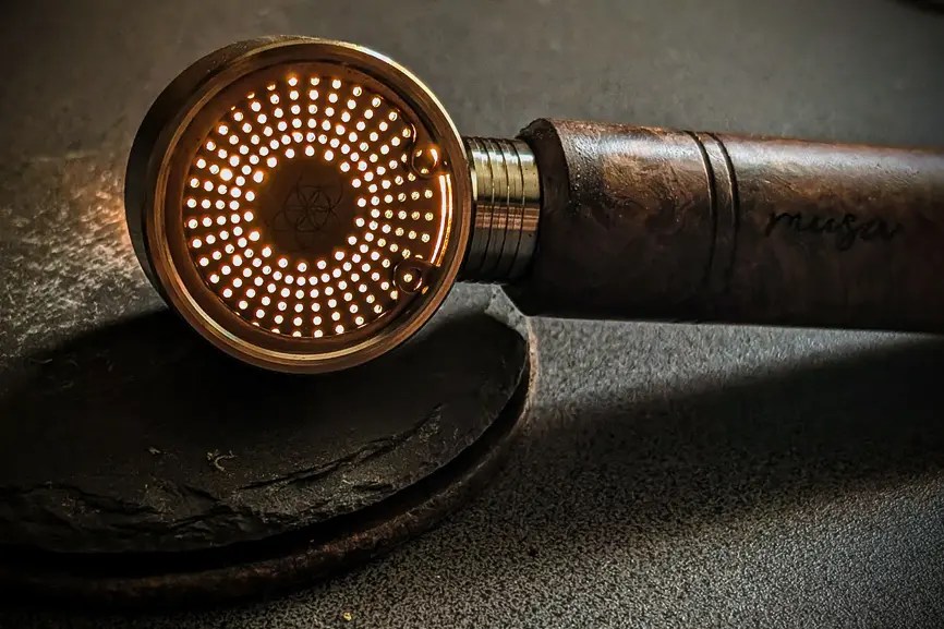 A detailed close-up view of the glowing heating element with circular openings of the Musa 3000 on a dark surface.