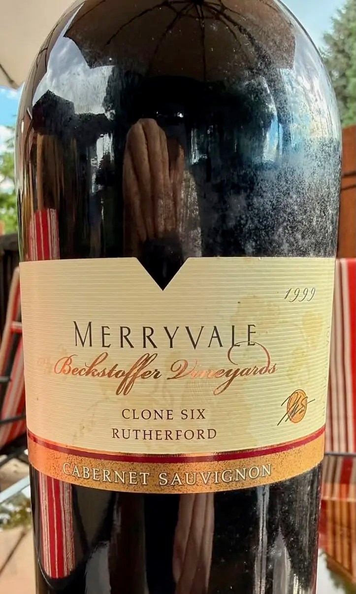 Close crop of a 1999 Merryvale Beckstoffer Vineyards Clone Six Cabernet Sauvignon from Rutherford, the label stained and the bottle sitting on an outdoor table.