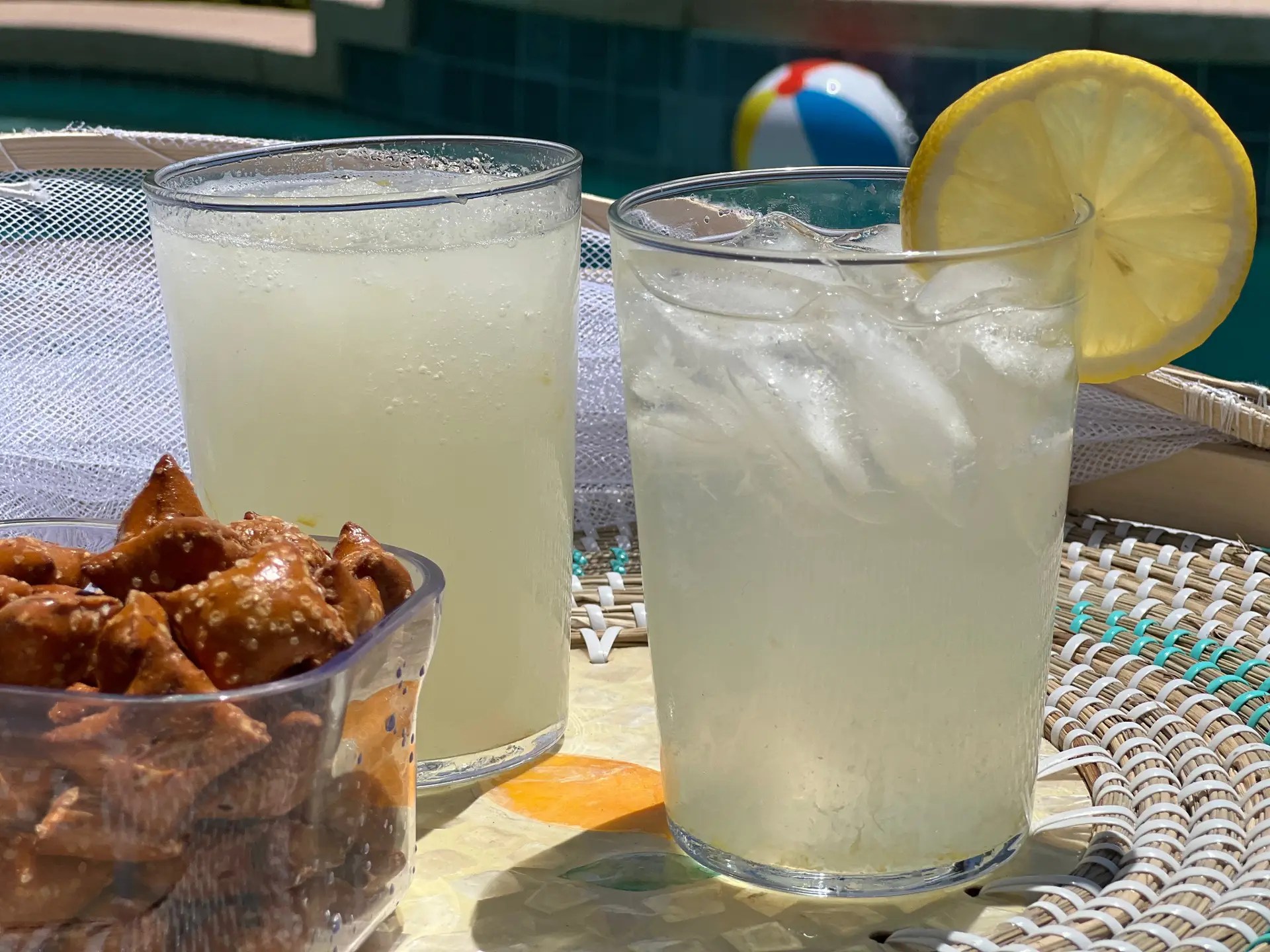 two Glasses of lemonade and bowl of pretzels poolside