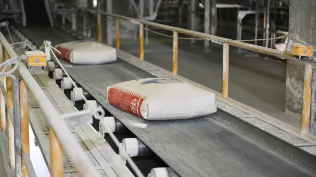 Bags of cement moving along a conveyor belt in a Portland cement manufacturing facility.