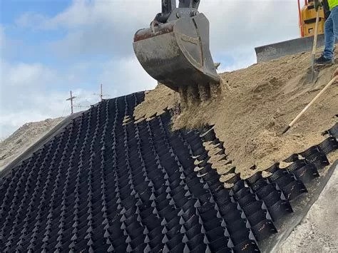 Excavator depositing soil on geocell structure for soil confinement and reinforcement in civil engineering.