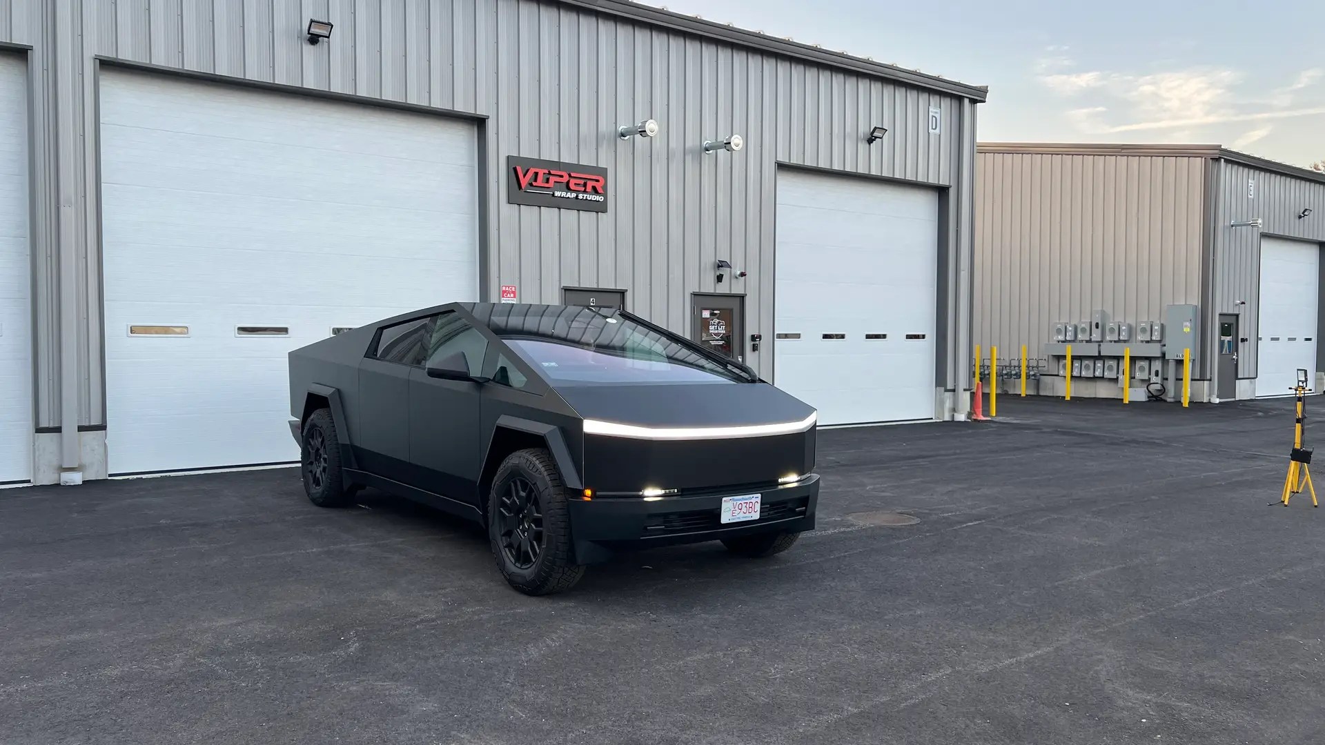 a Tesla Cybertruck wrapped in matte black by Viper wrap studio & car detailing, parked in front of the shop in pembrok ma