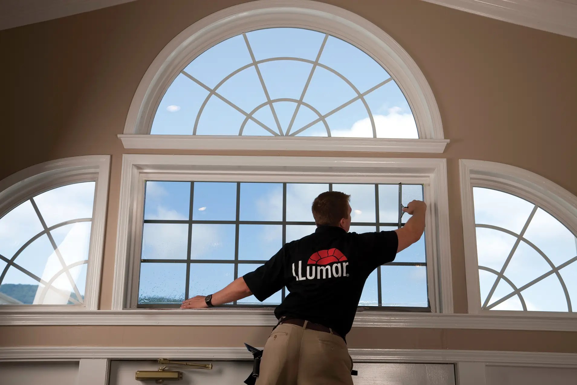 Llumar technician is installing residential and commercial window tint on a window in a clients's house