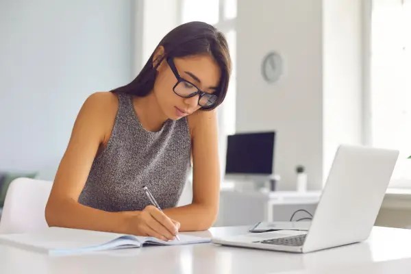 Woman reviewing health information on a laptop while taking notes, representing evidence-based decision-making when evaluating magnesium supplements