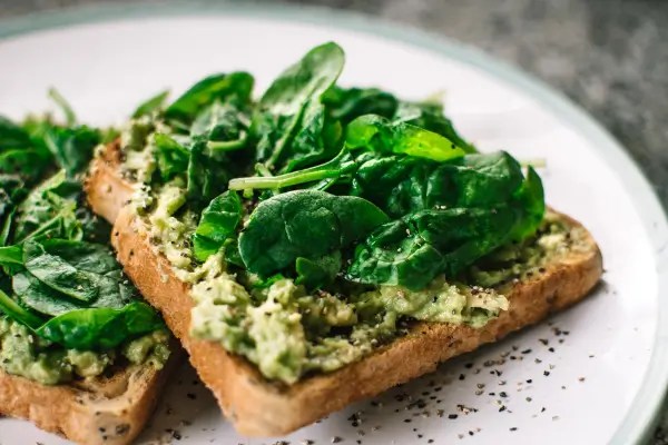 Avocado toast topped with fresh spinach, representing magnesium-rich foods that help support cellular energy production and metabolic health