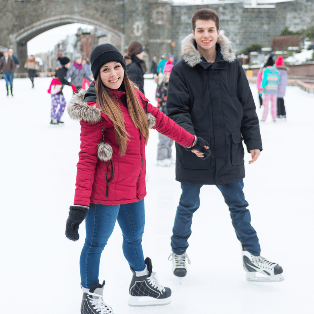 A man and woman enjoying the winter wonderland of Quebec in December as they gracefully glide across the ice rink, showcasing their ice skating skills.
