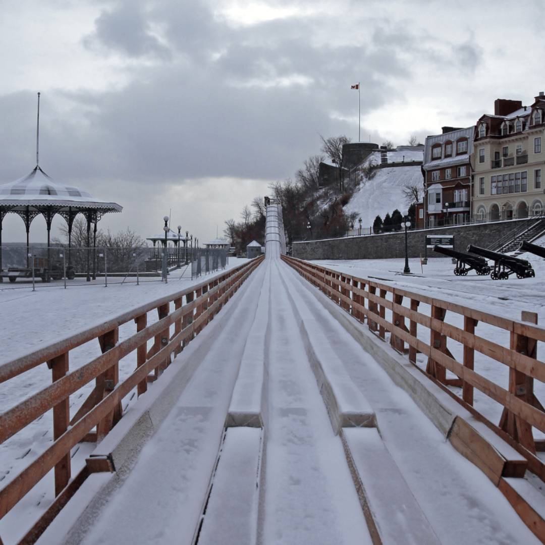 Visiting Quebec in winter, a wooden walkway leads to a gazebo on a snowy day.