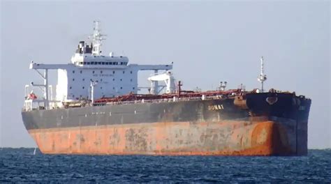 Aging oil tanker with a rust-streaked hull lying at anchor on open water.