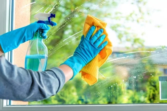 House cleaning professional cleaning a kitchen window