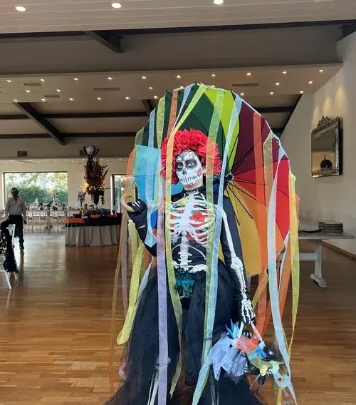 Day of the Dead character with rainbow ribbon parasol at a Halloween event