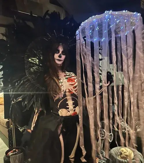 Gothic sugar skull performer with black feather crown and illuminated parasol