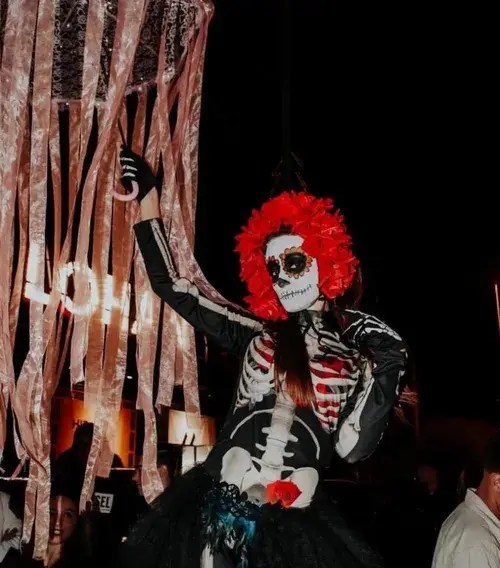Day of the Dead character with red rose crown at a Halloween night event