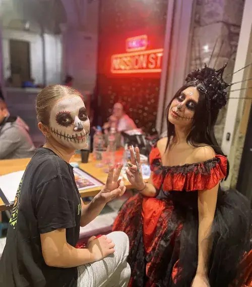 Halloween face painter with a guest in sugar skull makeup