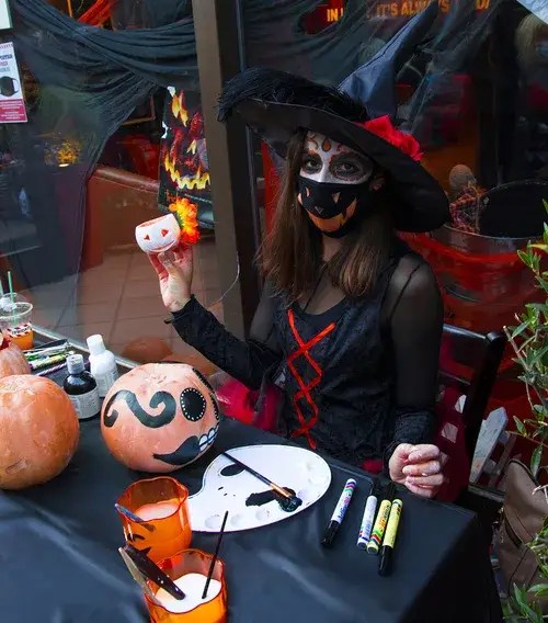 Witch pumpkin artist at a Halloween pumpkin painting station