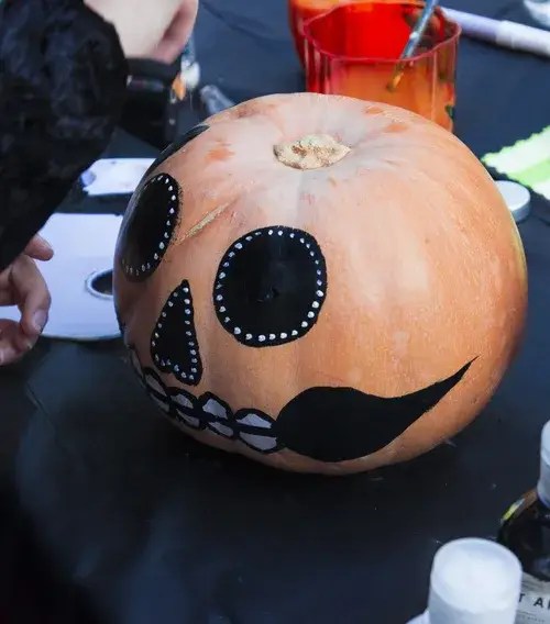 Hand painted sugar skull pumpkin at a Halloween activity station