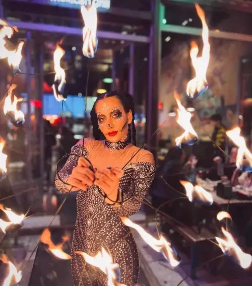 Halloween fire performer with sugar skull face paint and fire fans