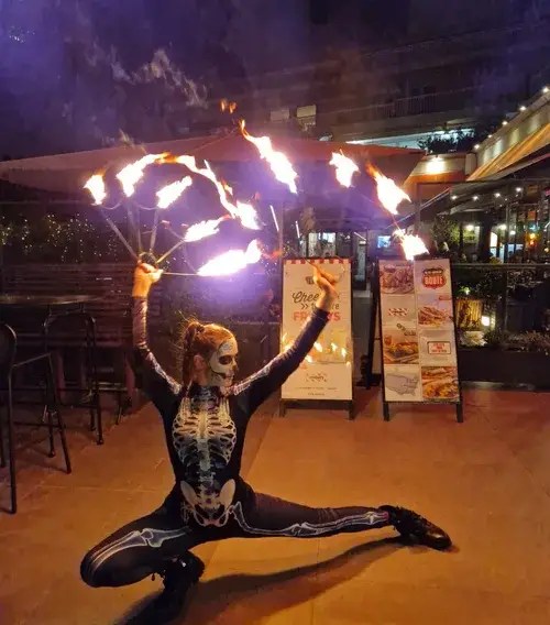 Skeleton costume fire dancer performing with fire fans outdoors