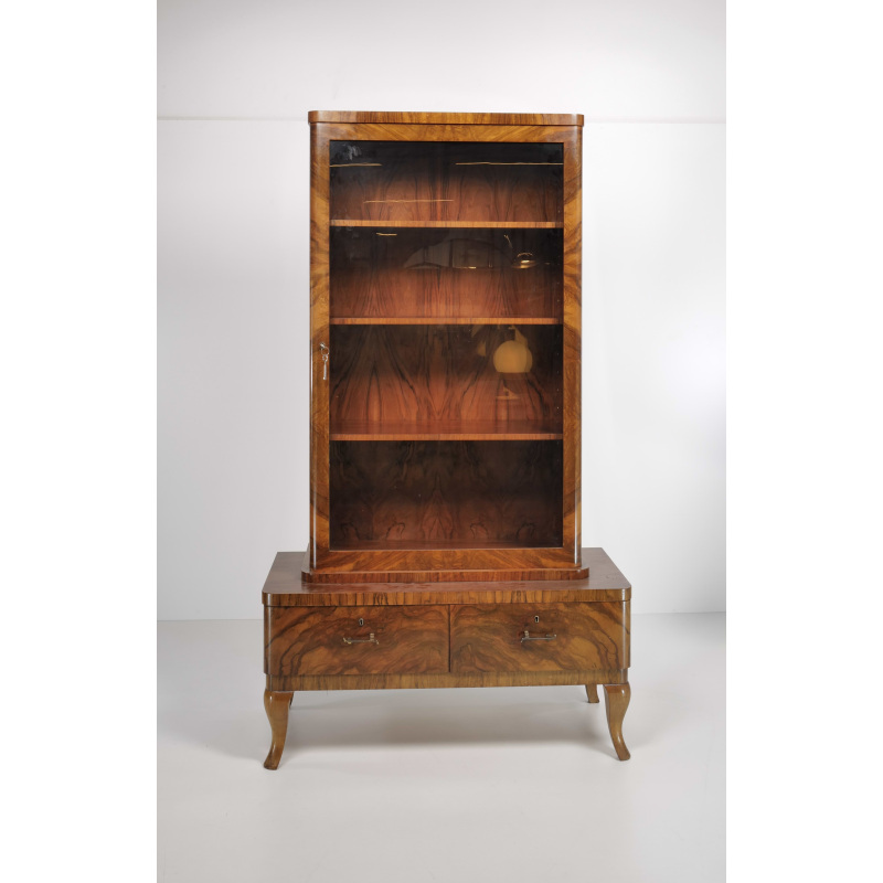 Tall antique wooden cabinet with glass-front door and two lower drawers on curved legs, empty interior shelves.
