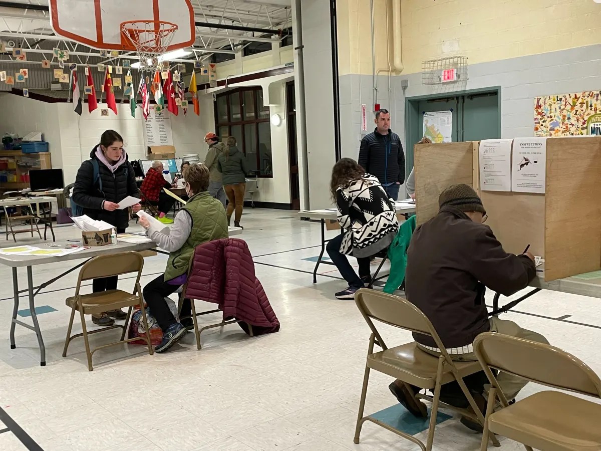 A group of people sitting at tables in a gym.