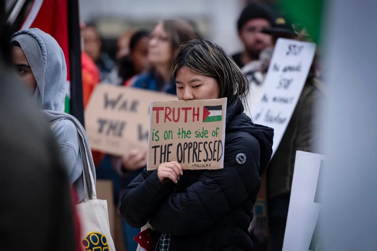 A woman holds up a sign in front of a crowd of people.