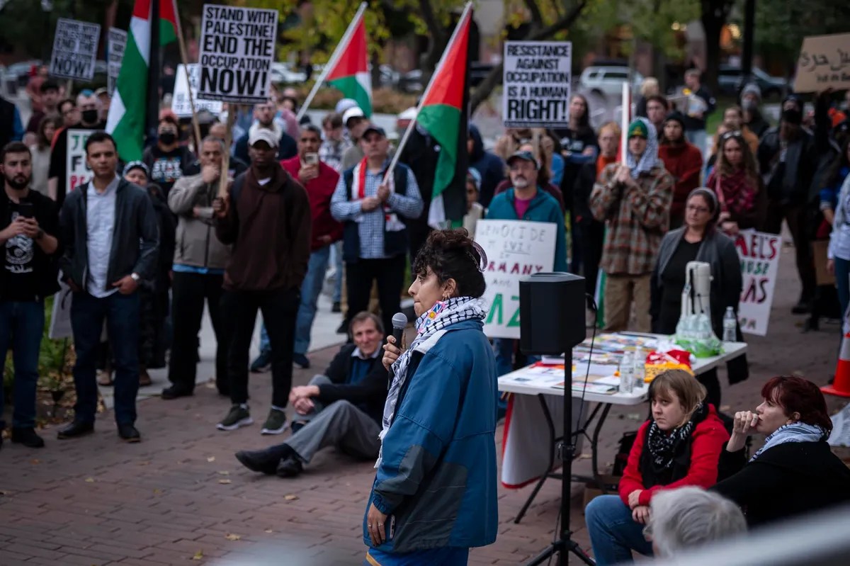 A group of people holding signs and flags in front of a building.