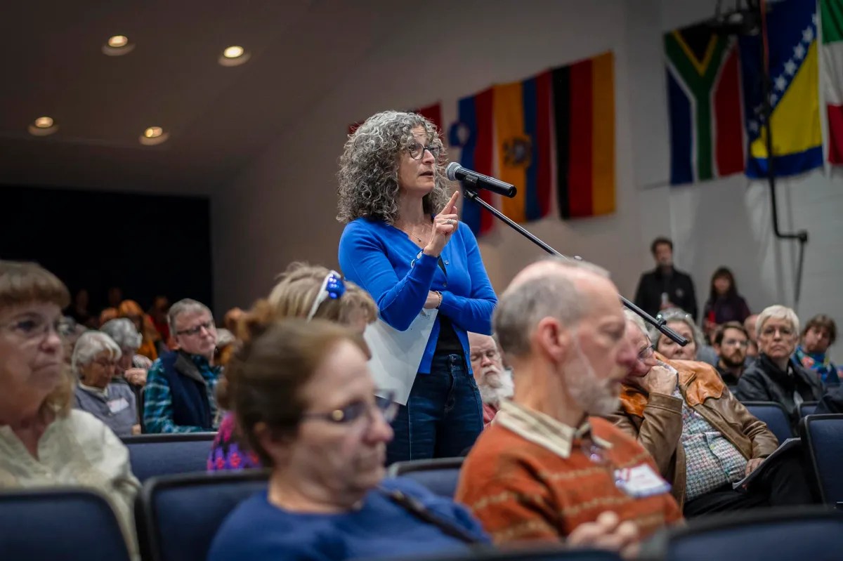 A woman speaking into a microphone in front of an audience.