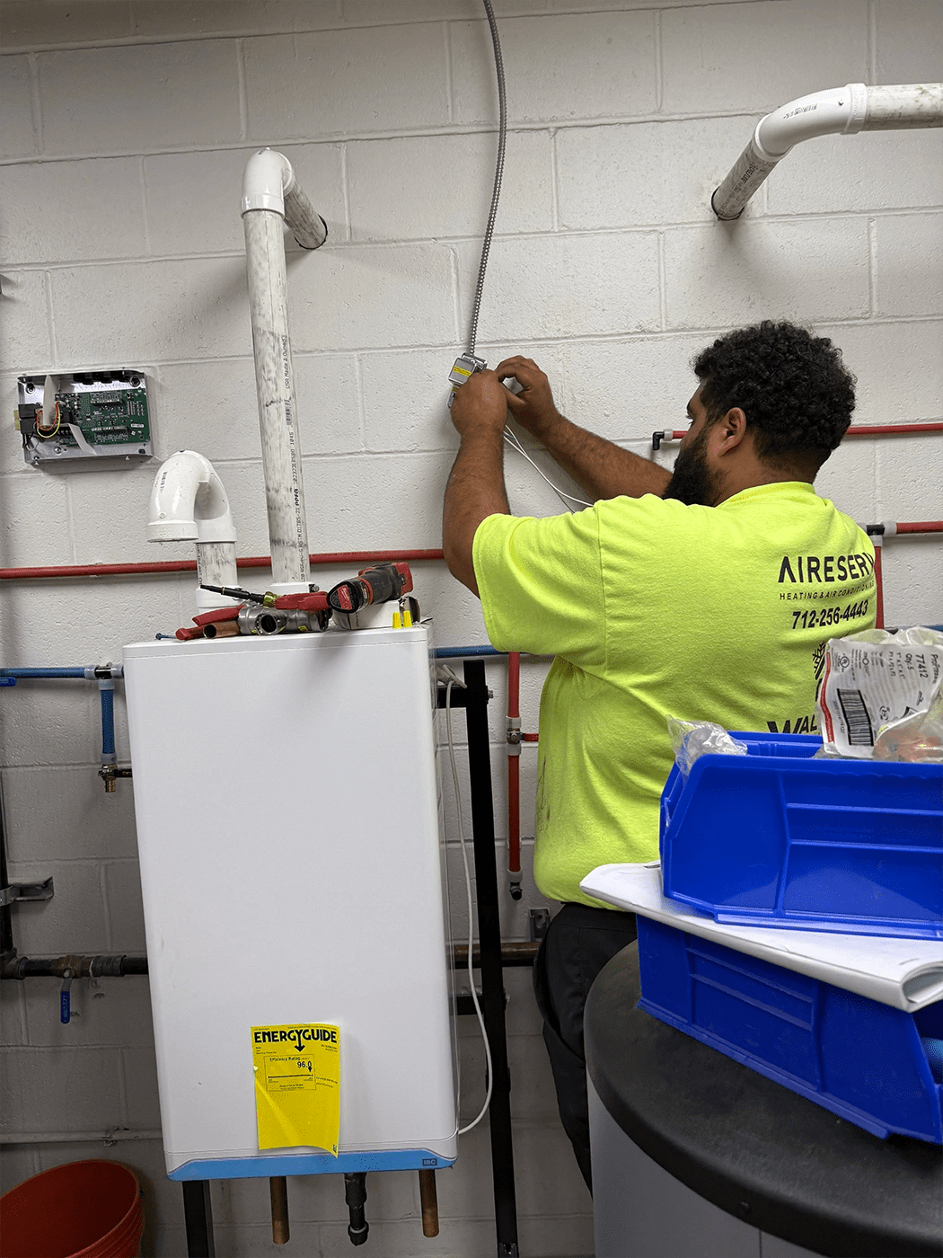 Man touching wire hanging on a wall next to a tankless water heater