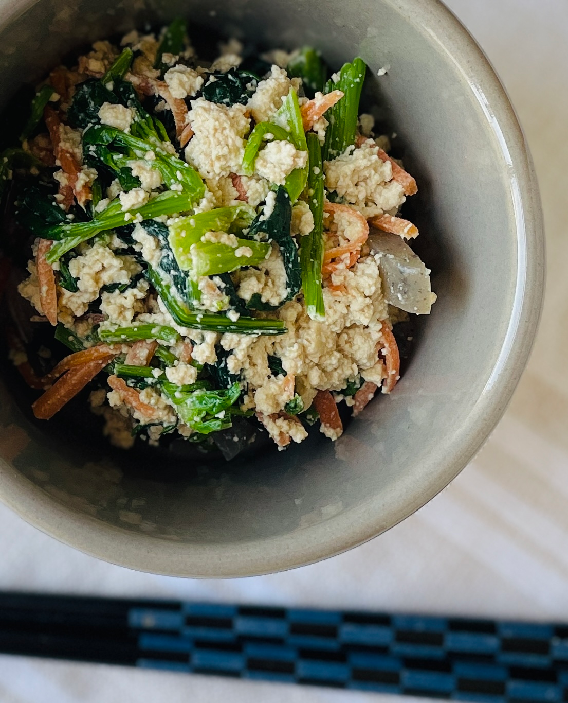 Japanese tofu sesame salad(shiraae) with spinach, carrots and konnyaku in a simple bowl.
