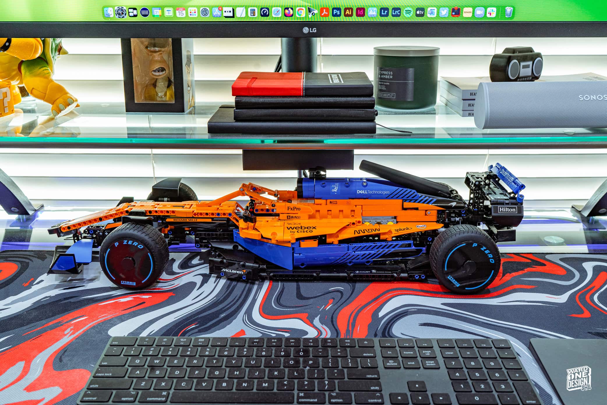 Detailed Lego model of a McLaren Formula 1 race car built with orange and black bricks, displayed on a desk with a keyboard in front.