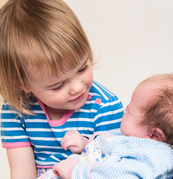 Warm Glow Photo f-6 Studio photograph of toddler holding her newborn baby sister by Anna Hindocha/Warm Glow Photo