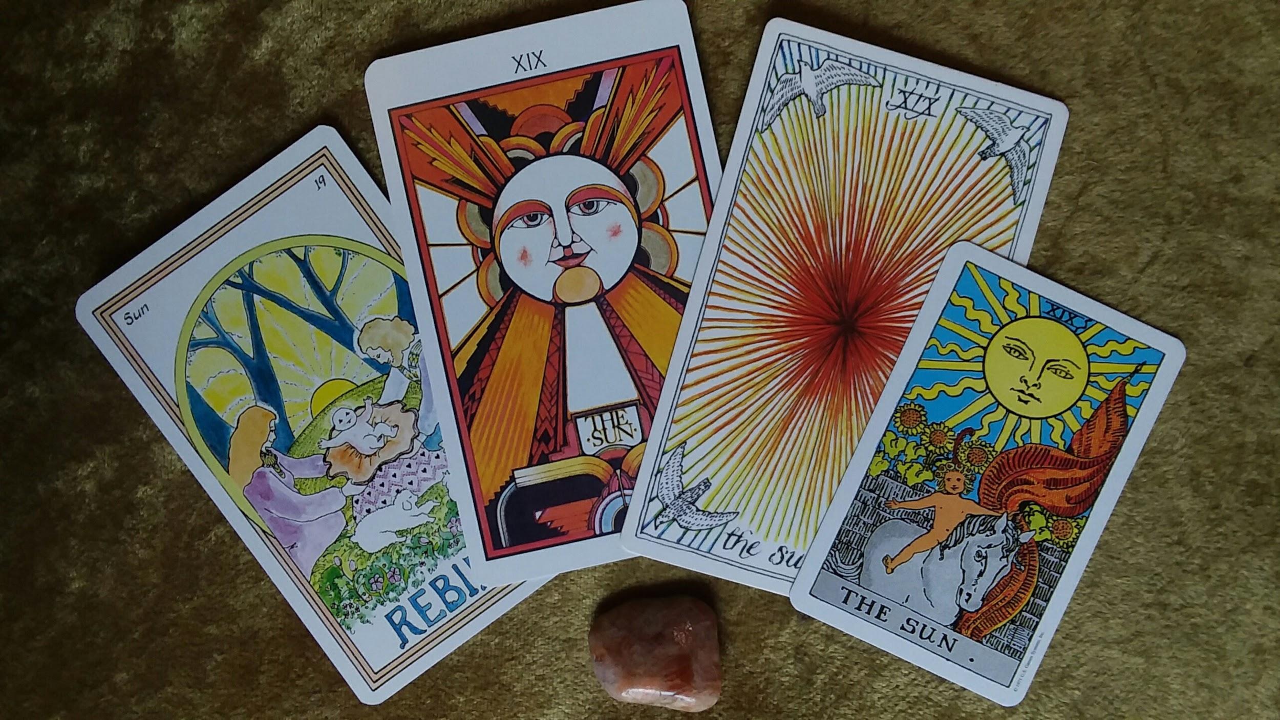 four sun cards from different tarot decks fanned out for summer solstice