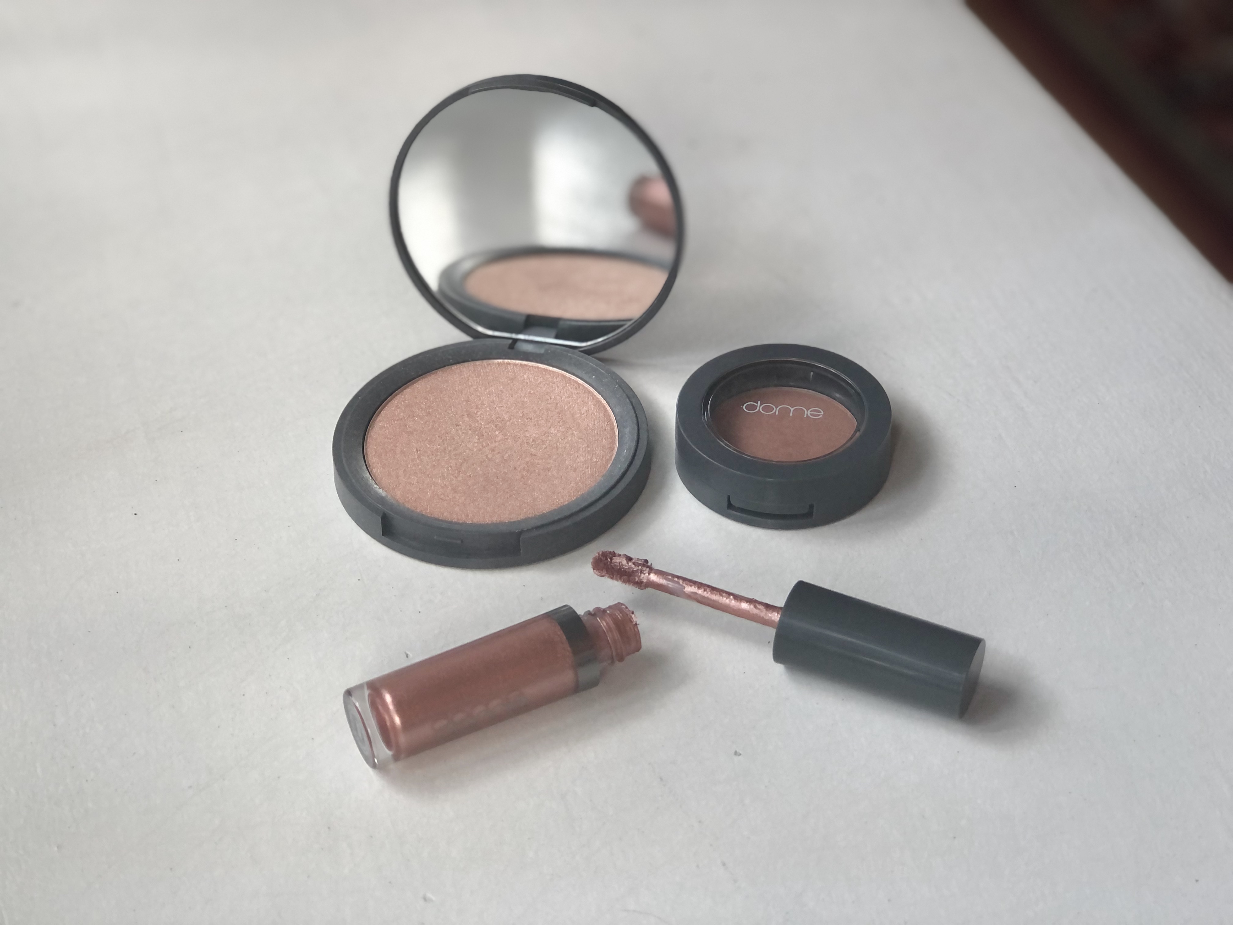 Products from indie beauty brand Dome Beauty, including a liquid eyeshadow, powder highlighter and powder blush